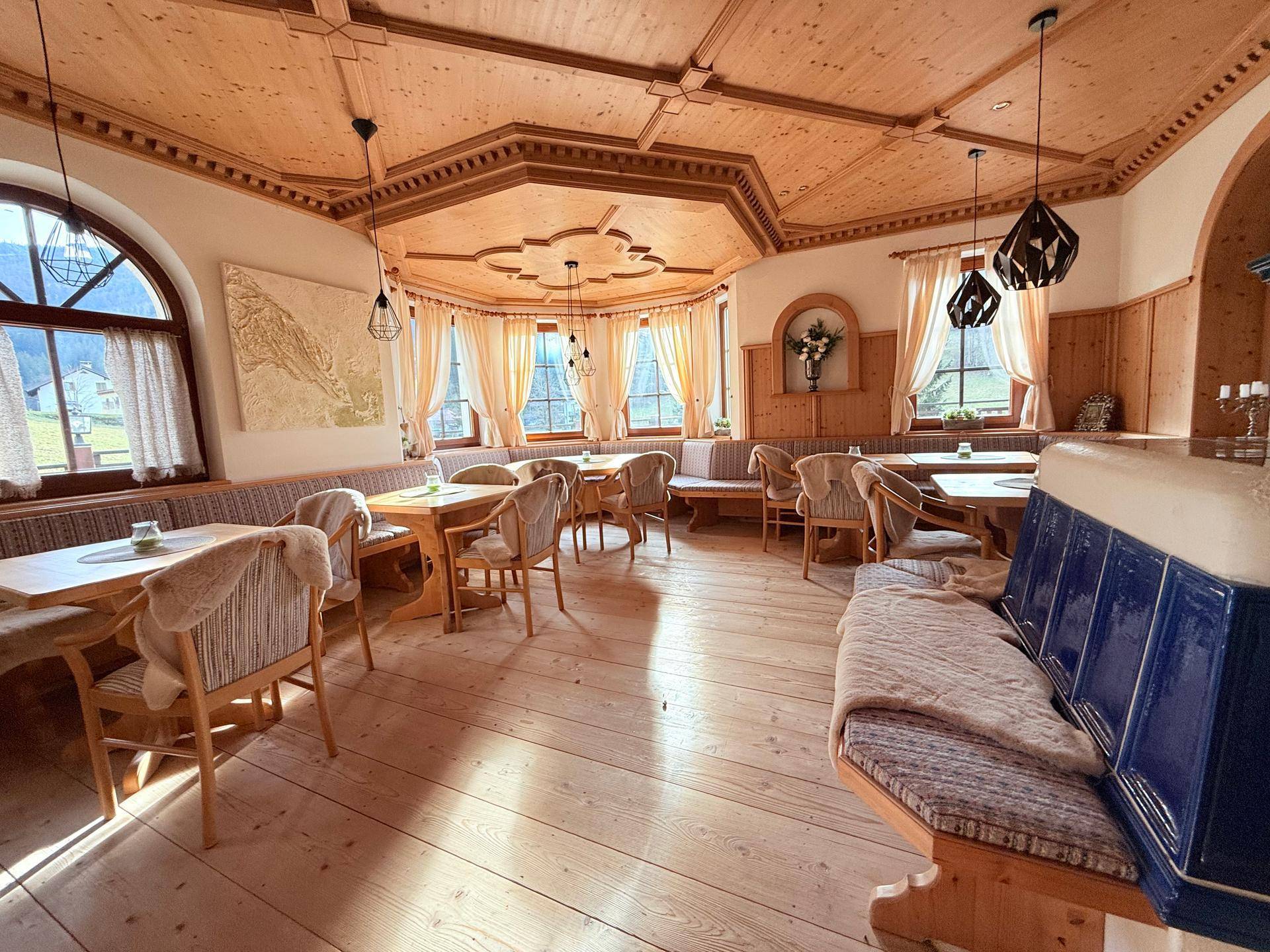 Gemütlicher Essbereich mit Holztäfelung, Holzboden und einem traditionellen blauen Kachelofen.