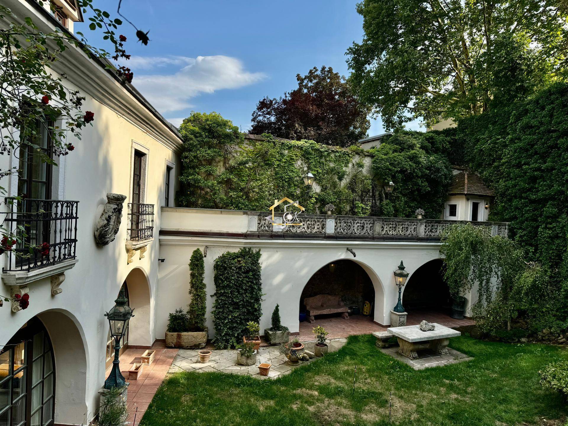 Malerischer Innenhof mit üppiger Vegetation, Steinbänken und einer historischen Gebäudearchitektur.