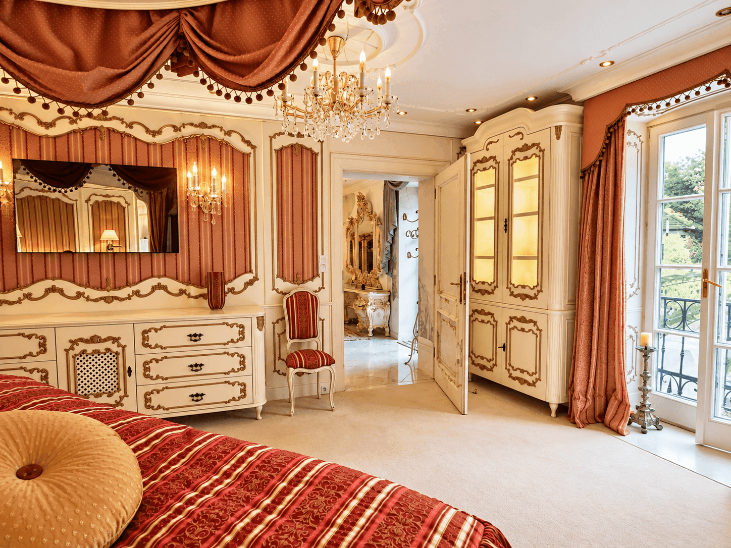 Elegantes Schlafzimmer mit luxuriösem Dekor, Kronleuchter und Zugang zu einem französischen Balkon.