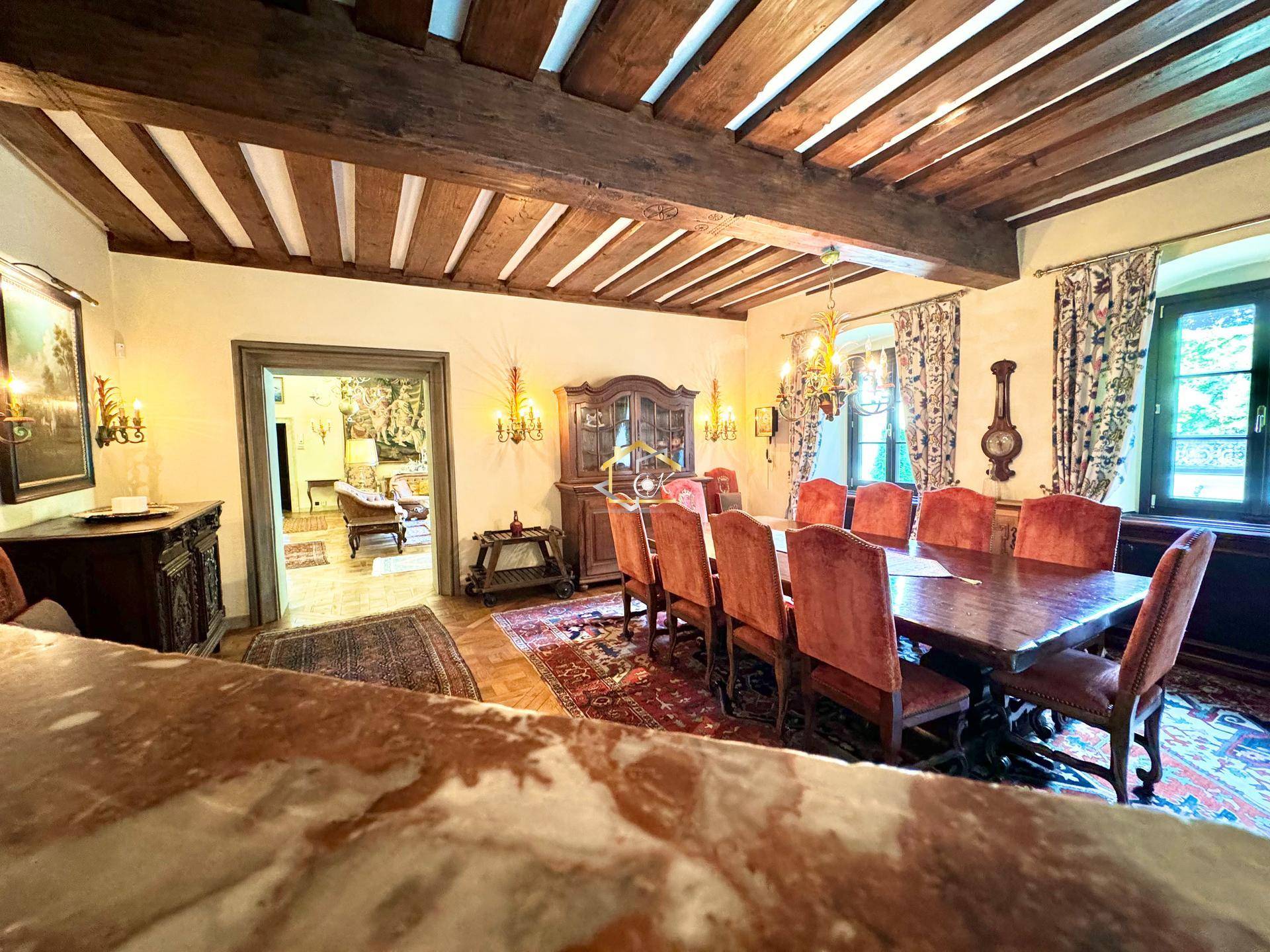 Traditionelles Esszimmer mit Holzbalkendecke, großem Esstisch und Blick in den Wohnbereich.