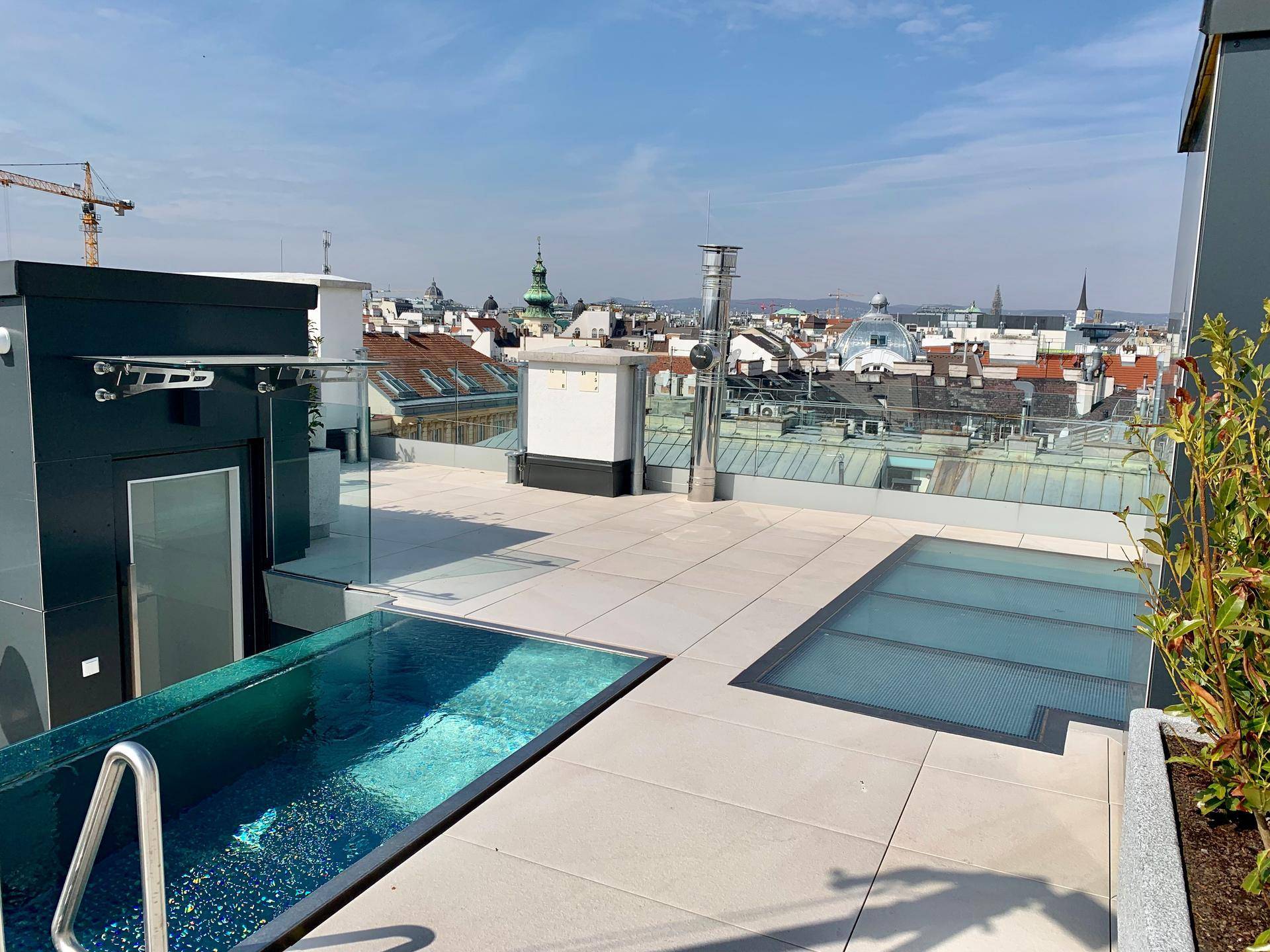 Dachterrasse mit Pool, Stadtblick und moderner Architektur unter blauem Himmel.