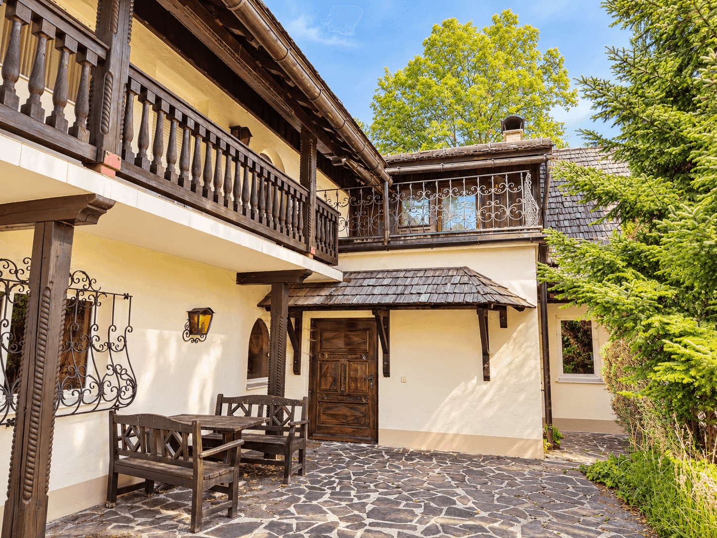 Gemütliche Terrasse mit Holzbänken und Tisch vor traditioneller Hausfassade.