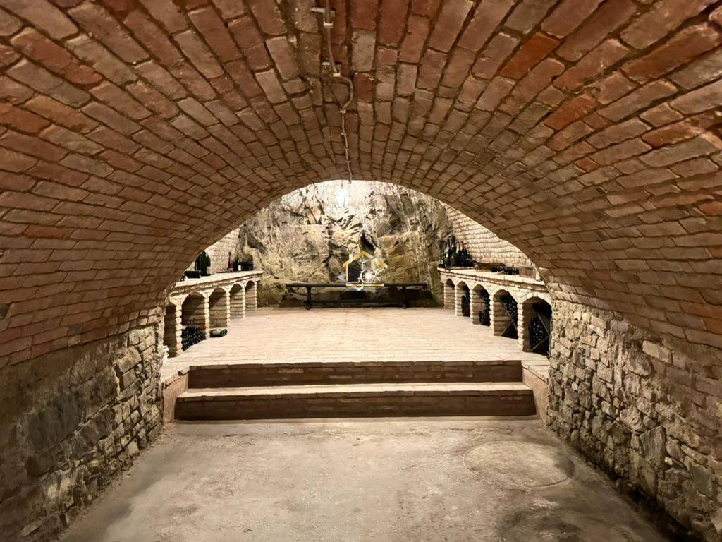 Historischer Weinkeller mit Ziegelgewölbe, Natursteinwänden und Weinregalen.