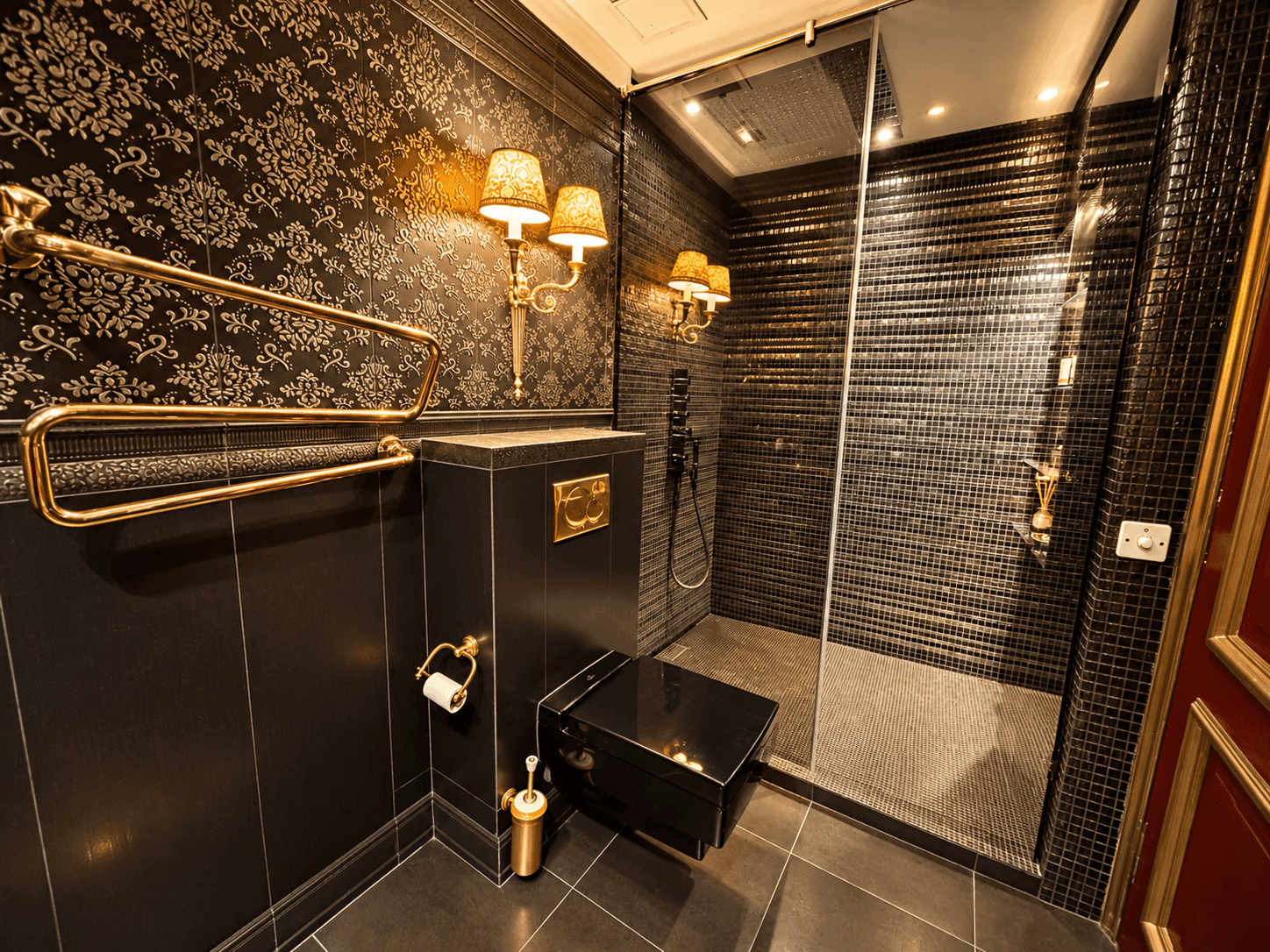 Modernes Badezimmer mit dunklen Fliesen, Duschkabine und goldfarbenen Armaturen.