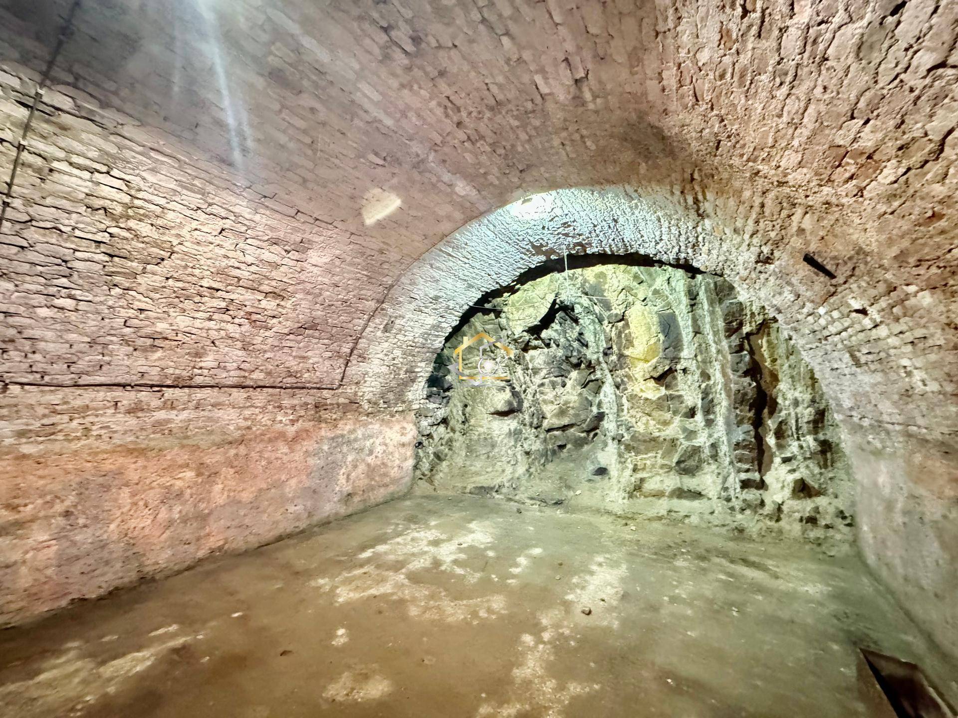 Rustikaler Gewölbekeller mit unverputzten Ziegelwänden und Naturstein.
