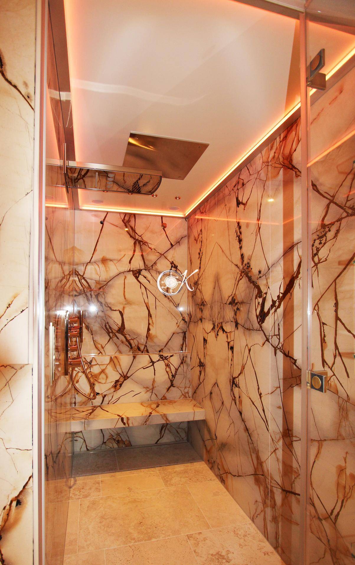 Elegante Duschkabine mit Steinverkleidung und indirekter Beleuchtung in einem luxuriösen Badezimmer.