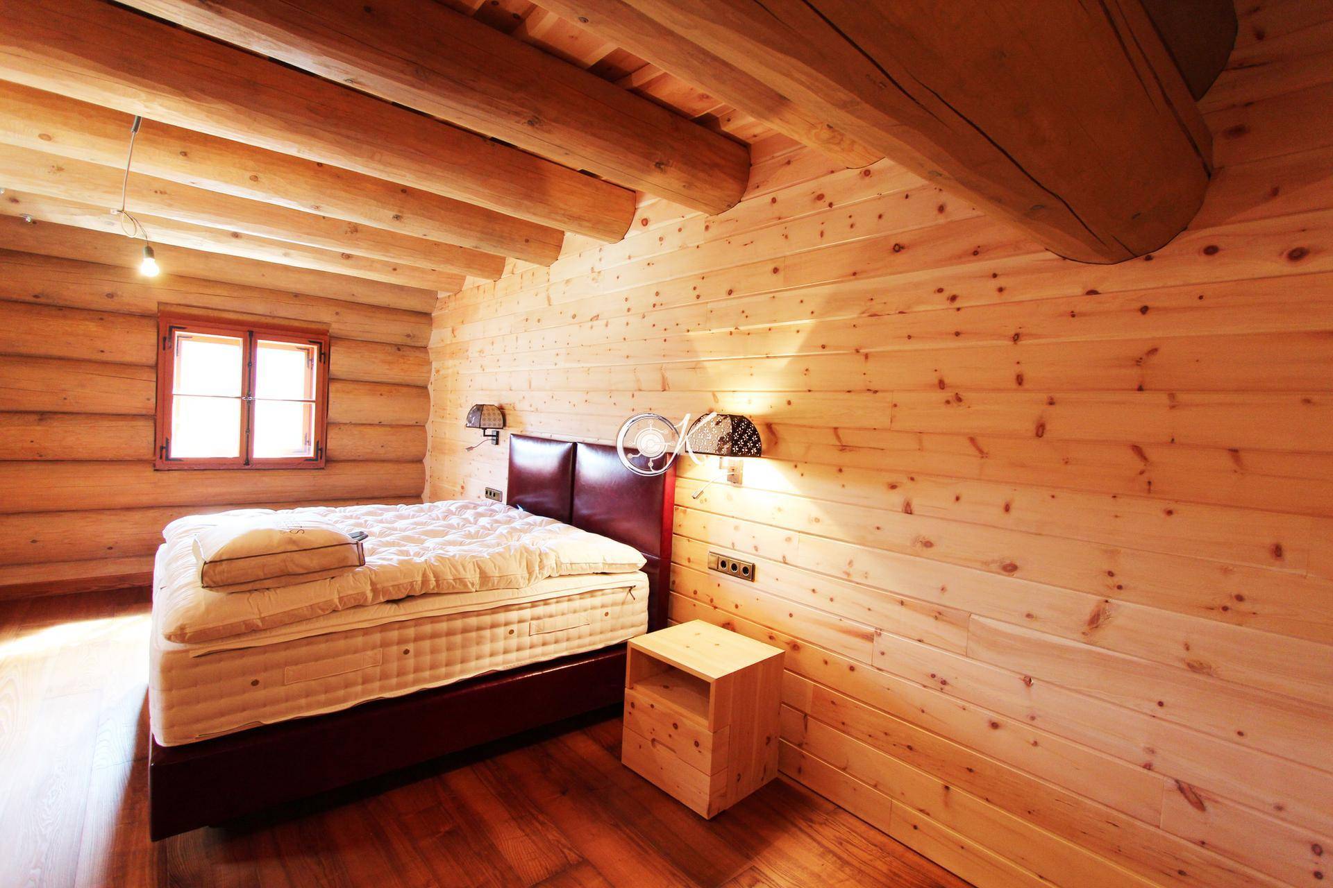 Gemütliches Schlafzimmer mit Holzwänden, Holzboden und einem bequemen Doppelbett.