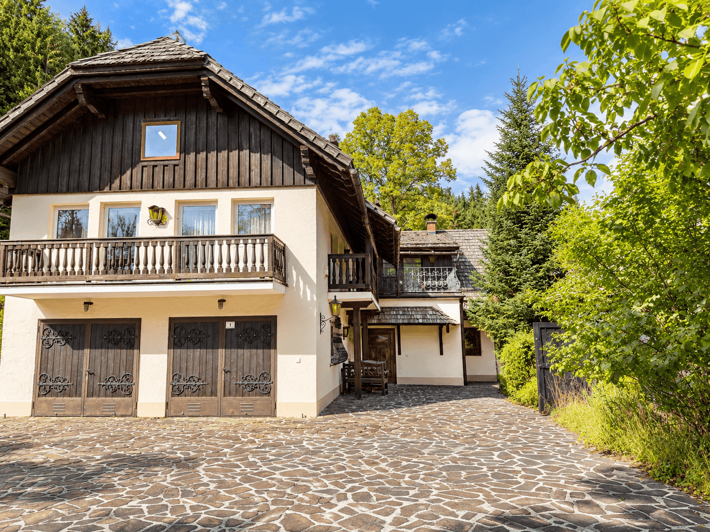 Charmantes Landhaus mit Doppelgarage, Holzbalkonen und gepflastertem Vorplatz.