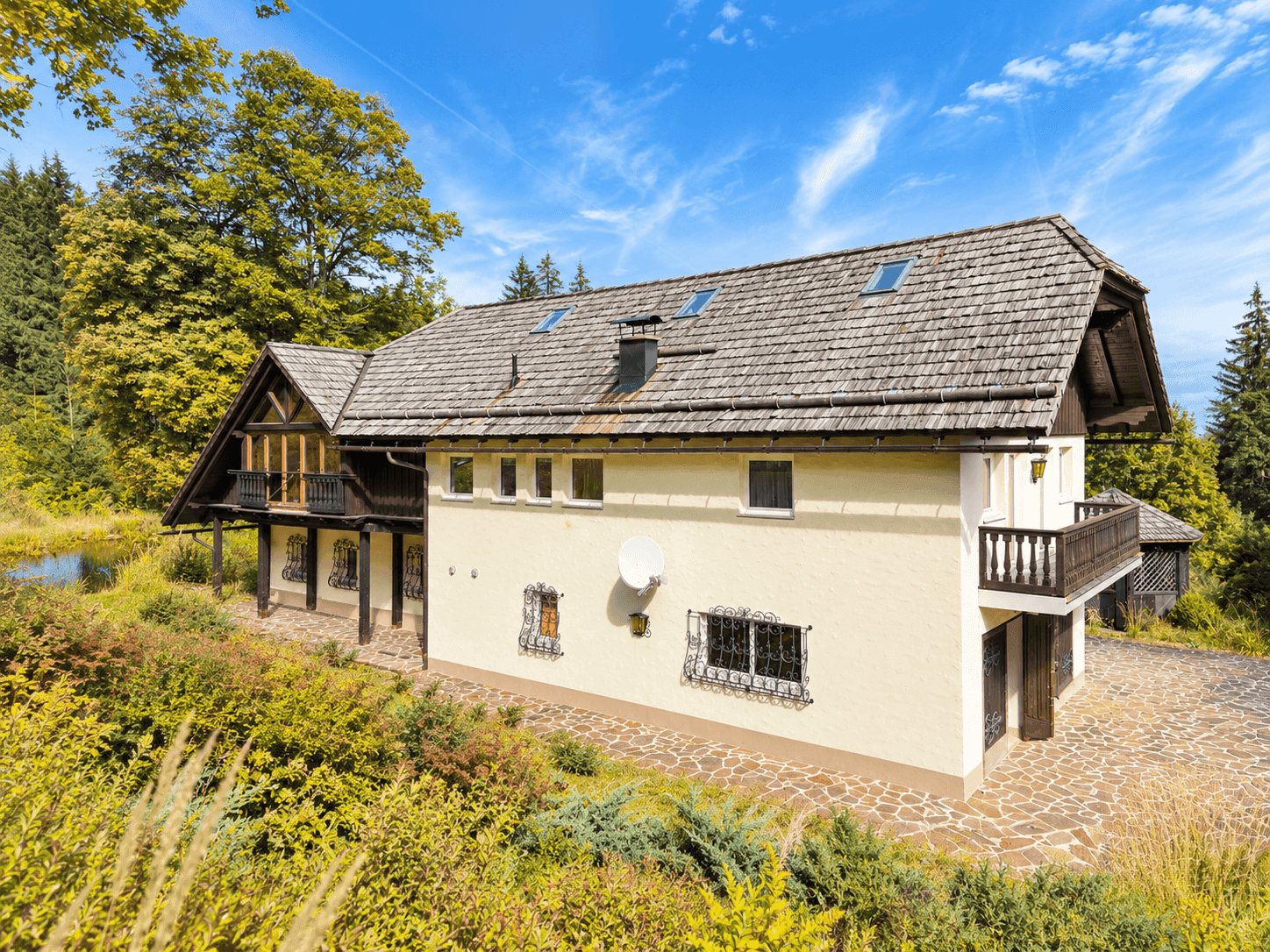Traditionelles Landhaus mit Holzbalkonen, Schindeldach und rustikalen Fenstergittern.