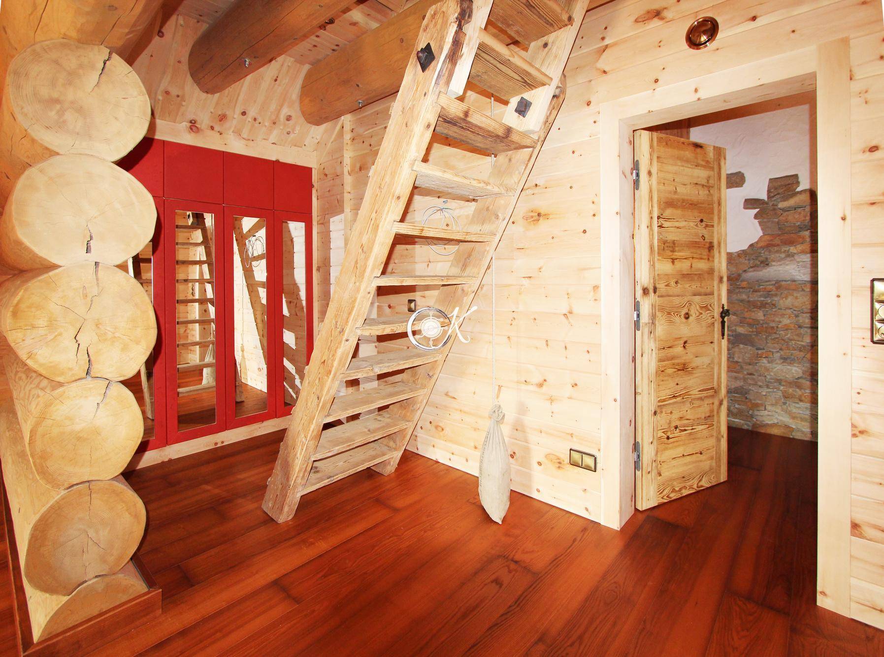 Rustikaler Raum mit Holztreppe, Holzwänden und einem roten Einbauschrank.