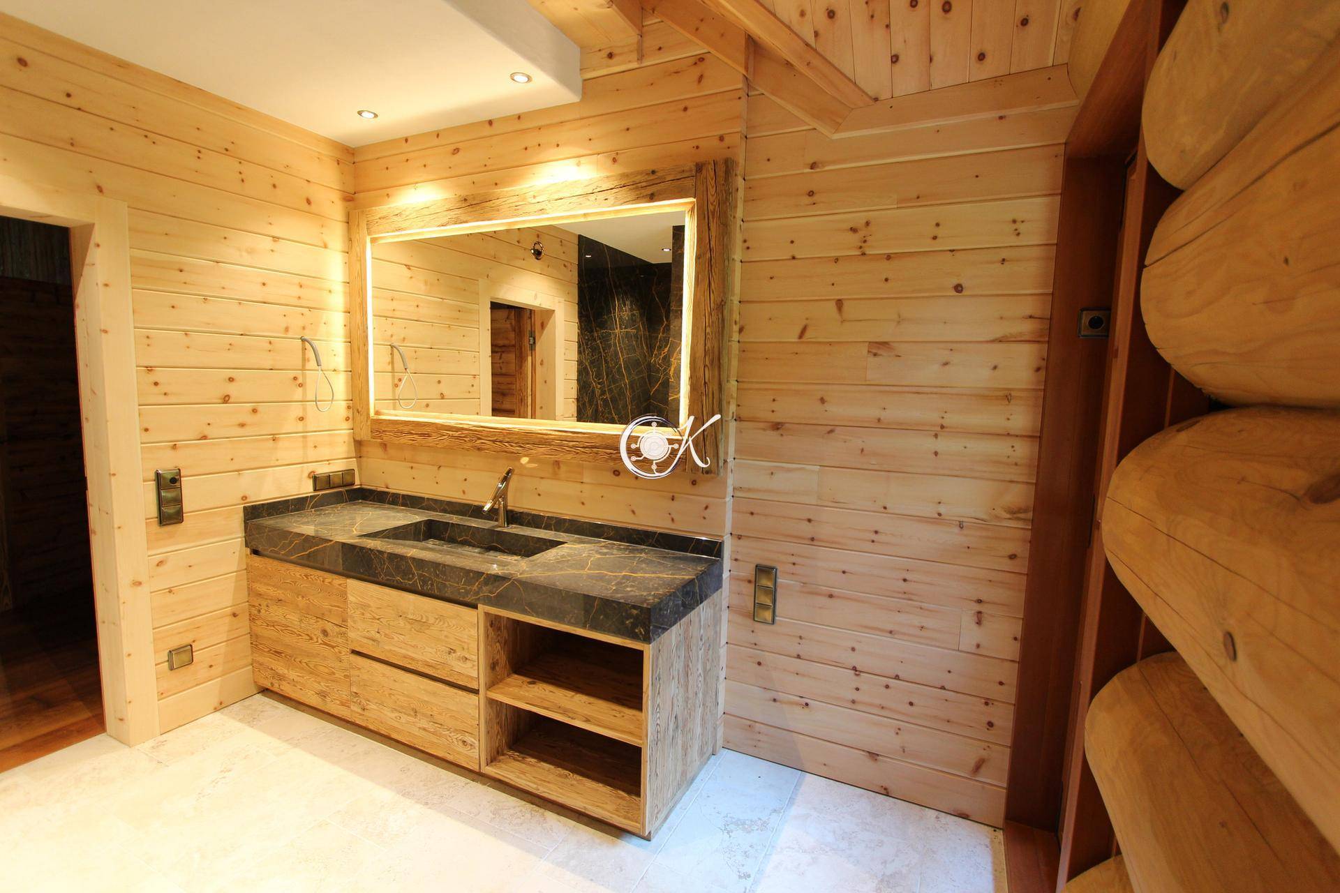 Modernes Badezimmer mit Holzwaschtisch, Steinplatte und beleuchtetem Spiegel.