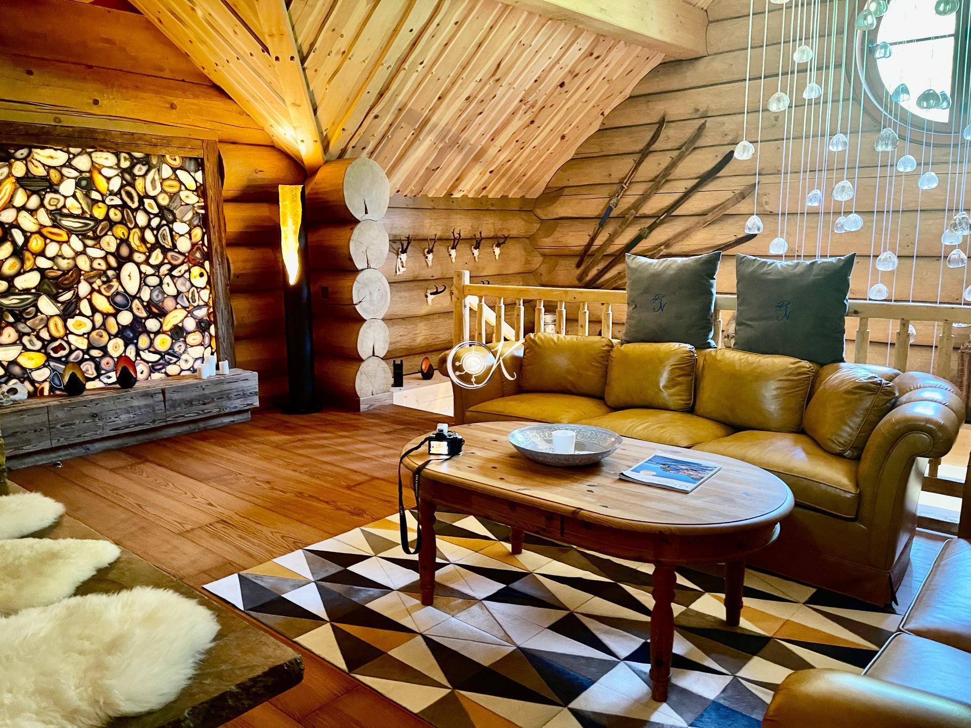 Gemütliches Wohnzimmer mit Ledersofas, Holzwänden und einer beleuchteten Steinwand als Akzent.