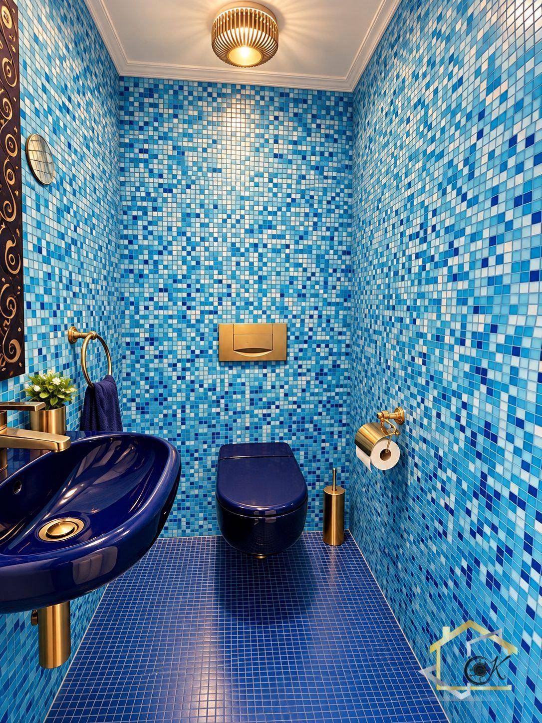 Farbenfrohes Gäste-WC mit blauen Mosaikfliesen, blauer Toilette und passendem Waschbecken.