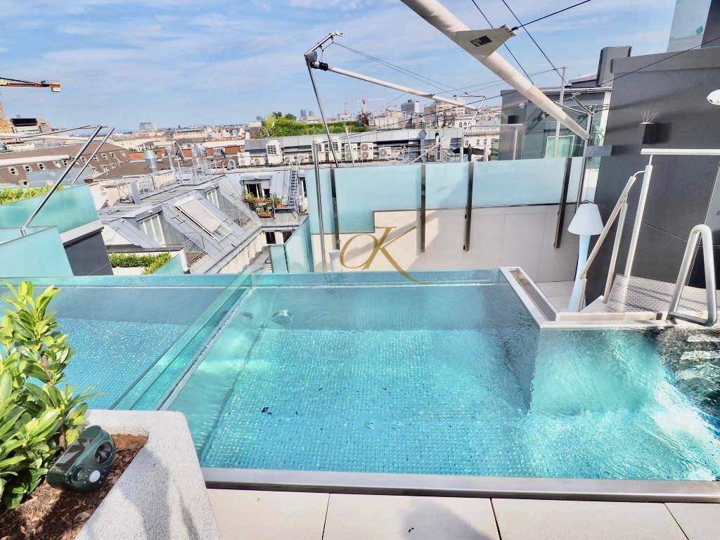 Dachterrasse mit Pool, Stadtblick und moderner Architektur unter blauem Himmel.