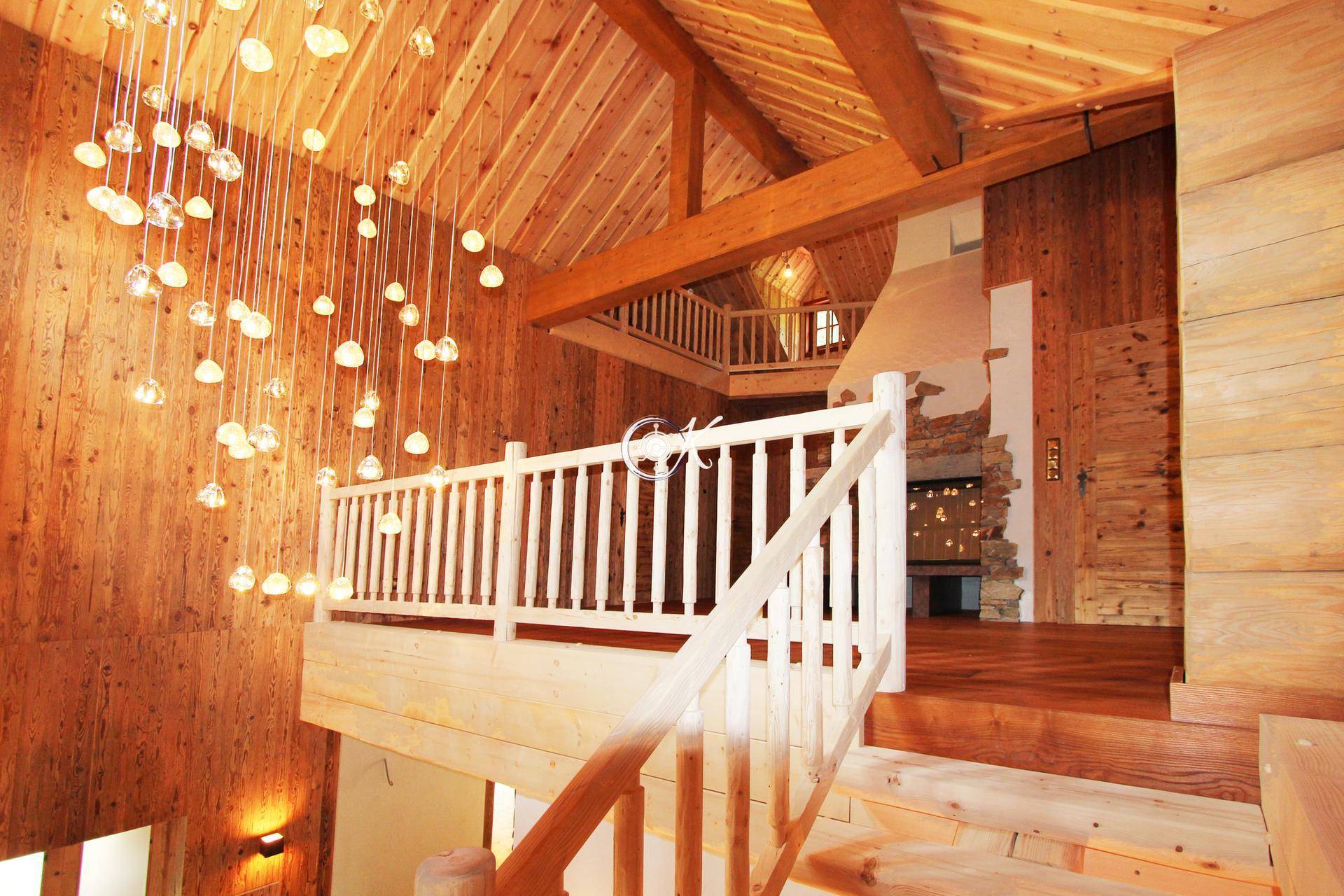 Helle Holztreppe mit Galerie und moderner Hängeleuchte in einem rustikalen Interieur.