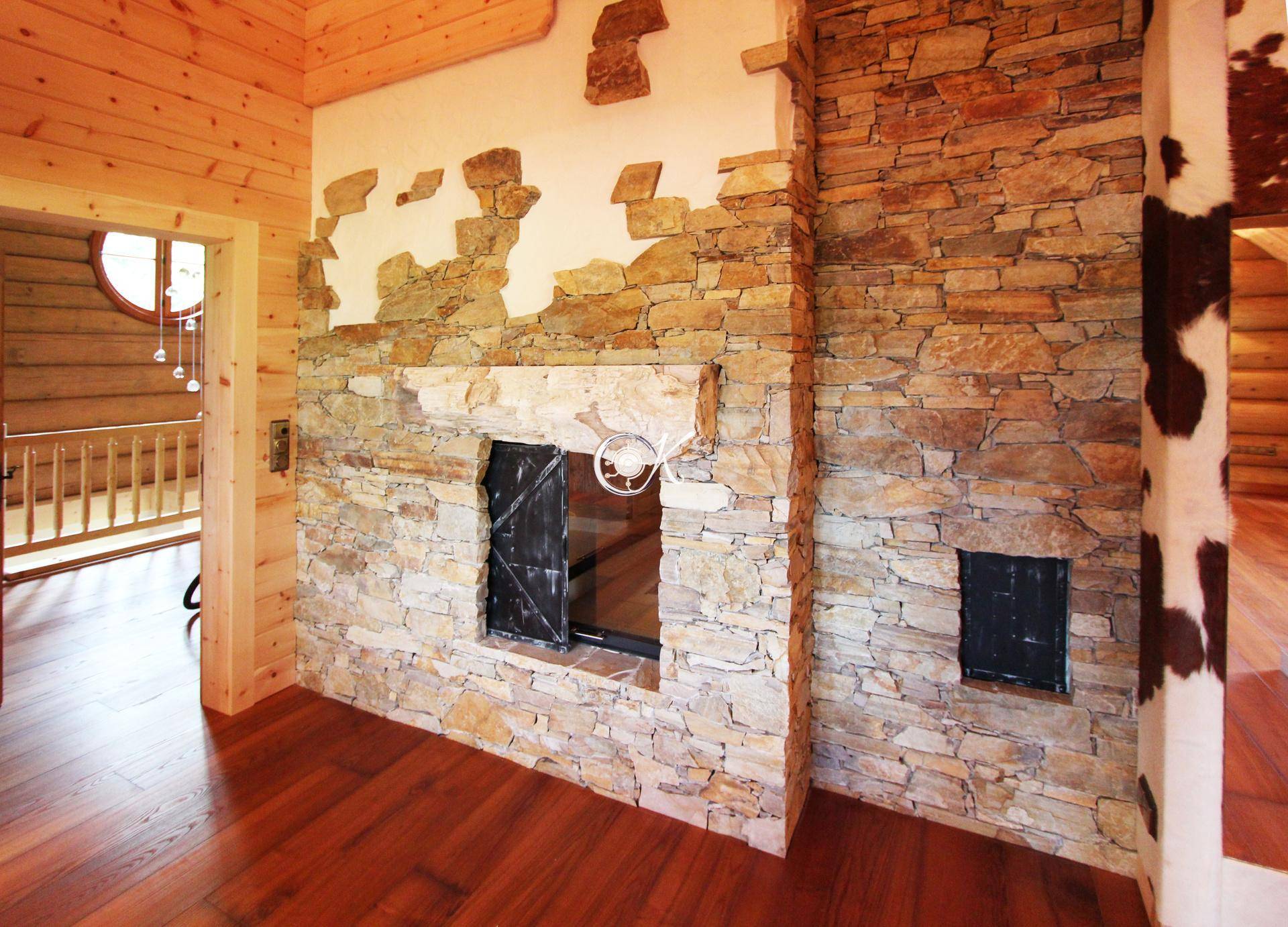 Rustikale Steinwand mit Kamin und Holzelementen in einem geräumigen Innenraum.
