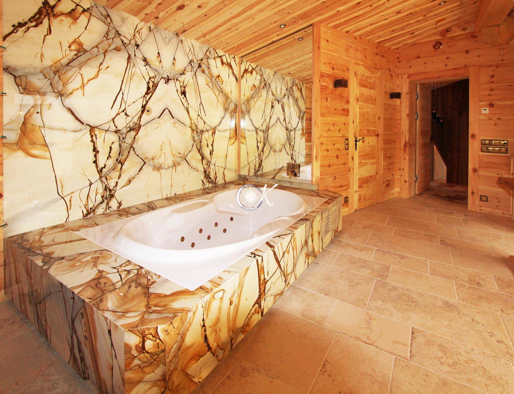 Luxuriöses Badezimmer mit Whirlpool-Badewanne, Steinverkleidung und Holzwänden.