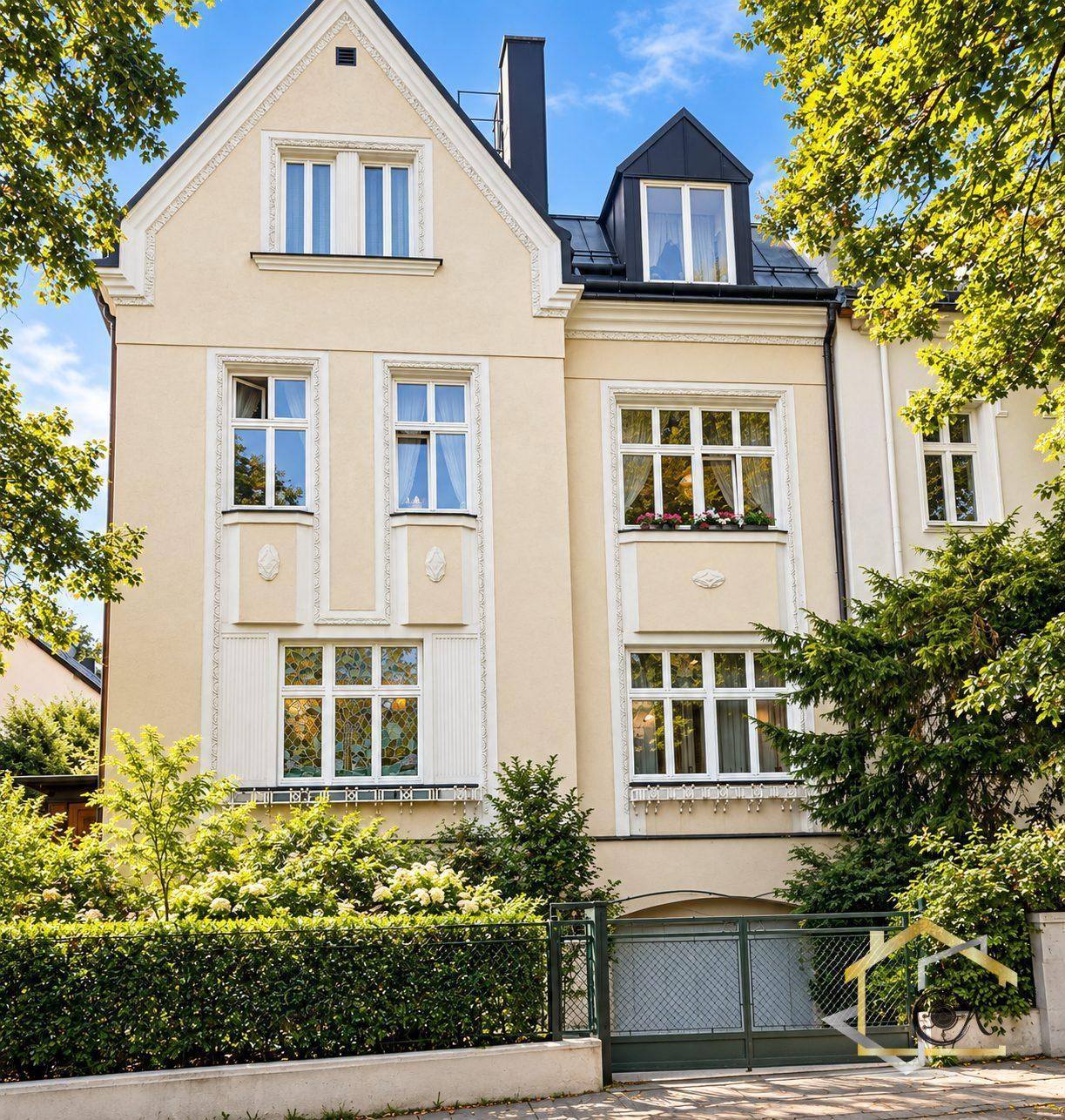 Klassische Stadtvilla mit heller Fassade, vielen Fenstern und gepflegter Hecke im Vorgarten.