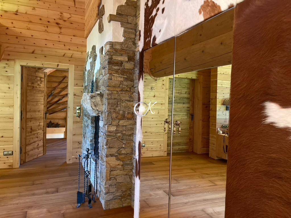 Detailansicht einer Steinwand mit Kamin und Spiegel in einem rustikalen Raum.