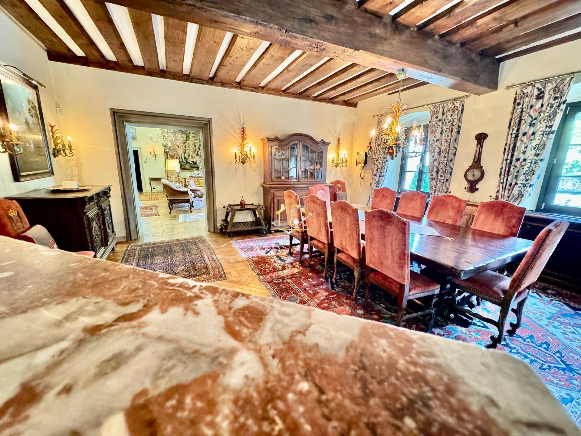 Geräumiges Esszimmer mit Holzbalkendecke, großem Holztisch und Samtstühlen.