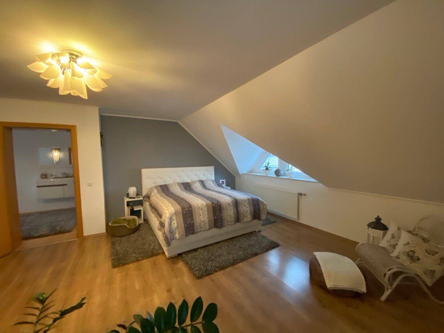 Gemütliches Schlafzimmer mit Doppelbett, Holzboden und schrägen Wänden im Dachgeschoss.