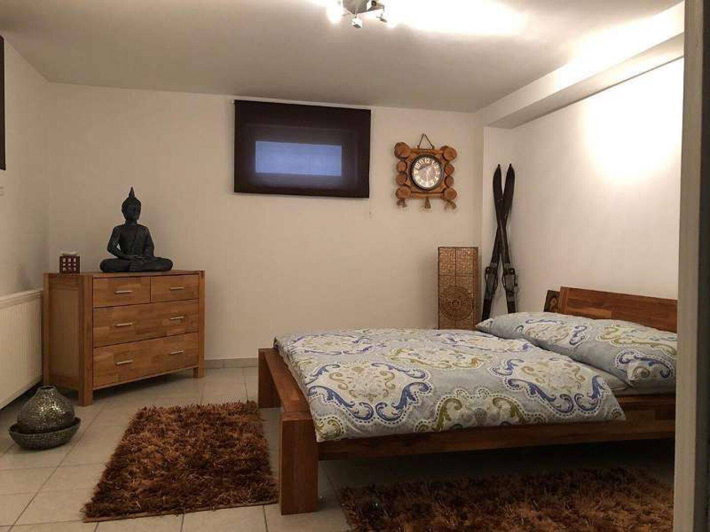 Schlafzimmer mit Holzbett, Fliesenboden und rustikaler Dekoration, ideal für Gäste.