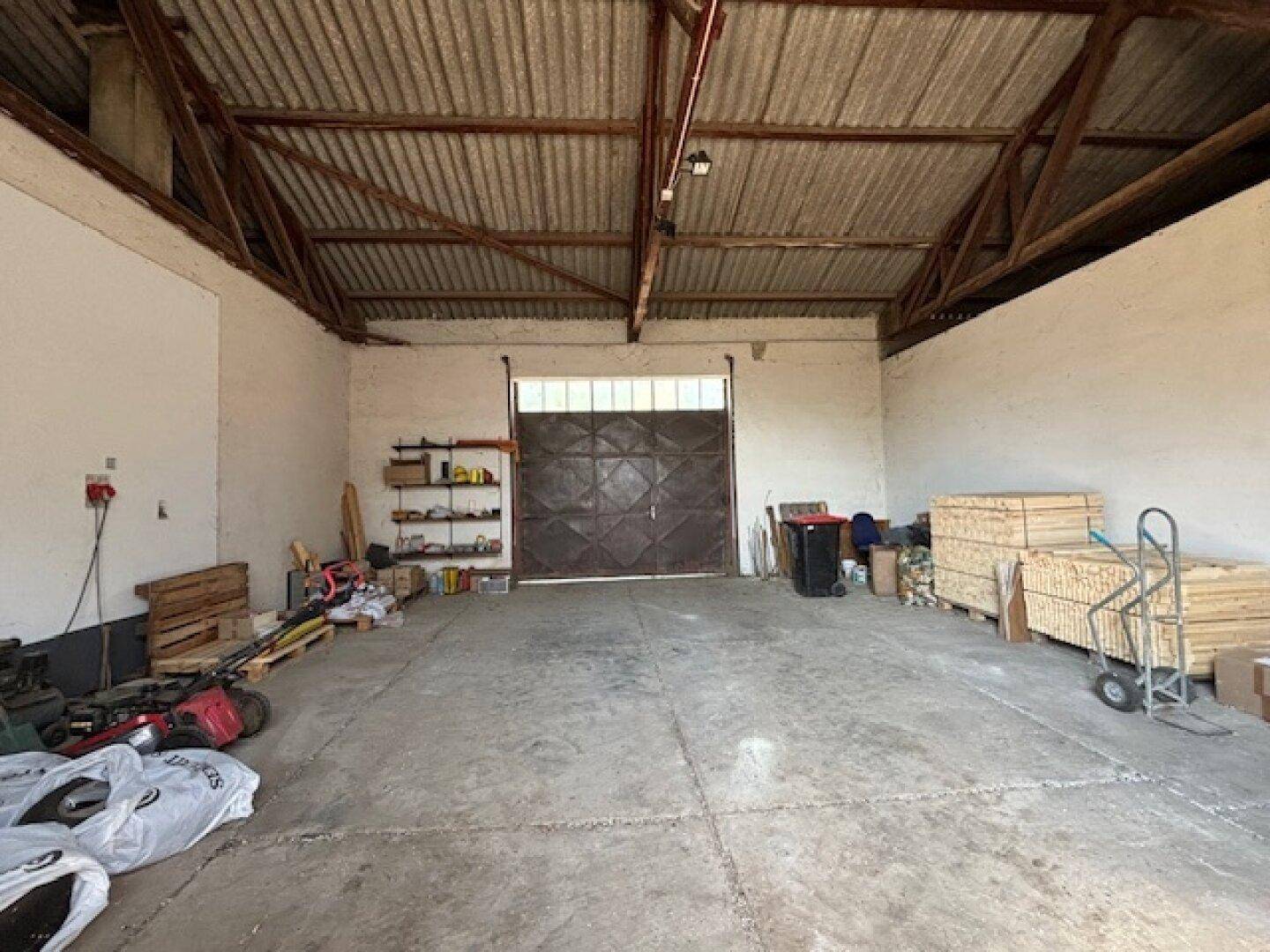 Geräumige Garage oder Lagerhalle mit Betonboden und großem Tor.