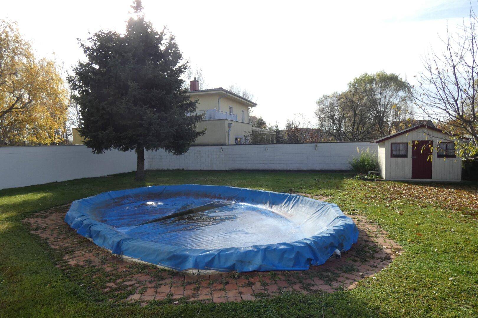 Großer Gartenbereich mit abgedecktem Pool und einem kleinen Gartenhaus im Hintergrund.