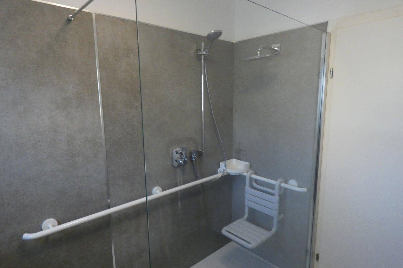 Barrierefreie Dusche mit Haltegriffen und Duschsitz für erhöhte Sicherheit und Komfort.