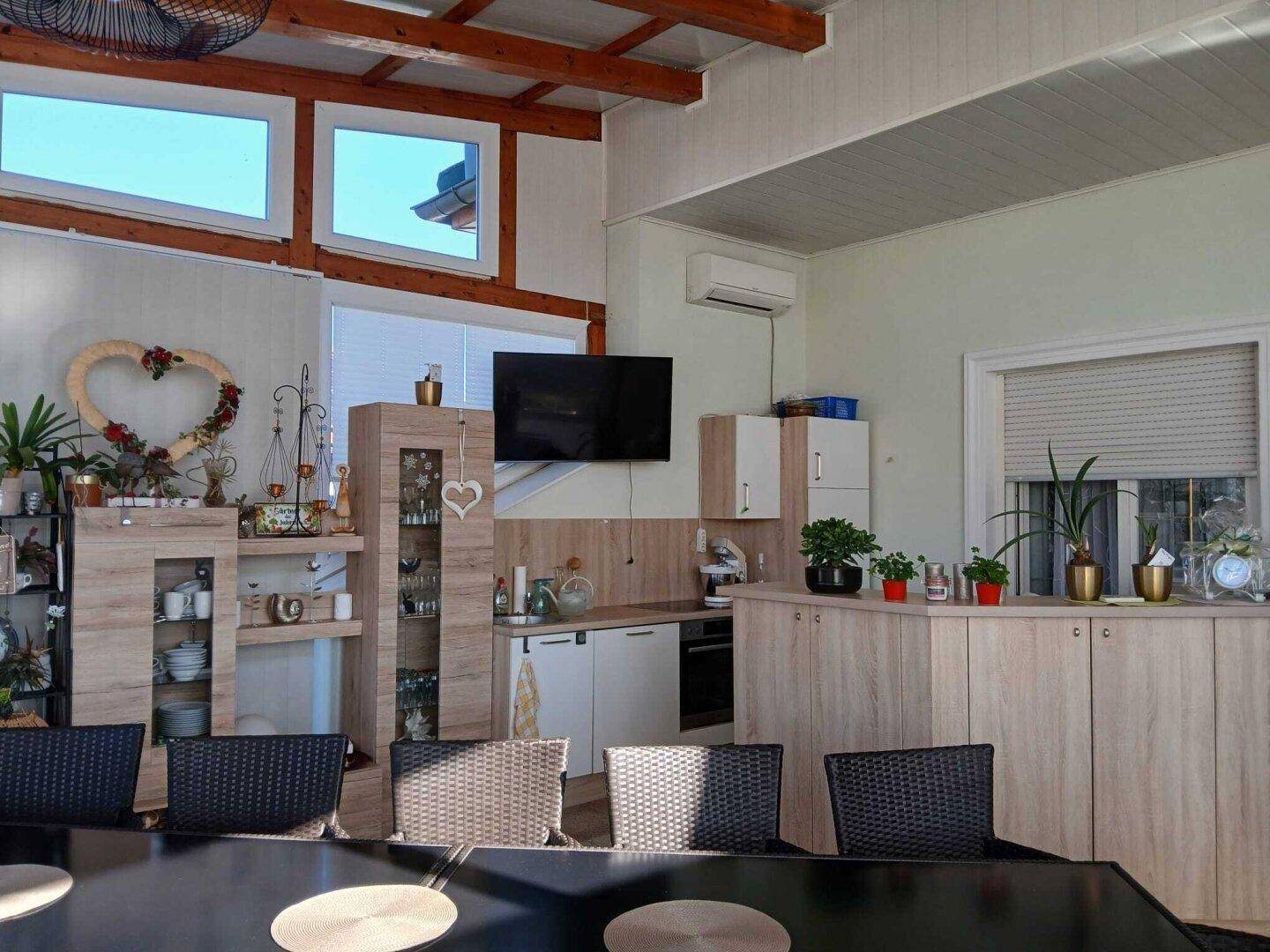Kleine Küchenzeile in einem hellen Raum mit Holzdetails, Klimaanlage und Blick nach draußen.