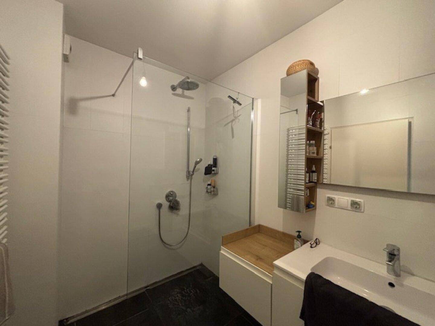 Modernes Badezimmer mit ebenerdiger Dusche, Einzelwaschbecken und dunklen Bodenfliesen.