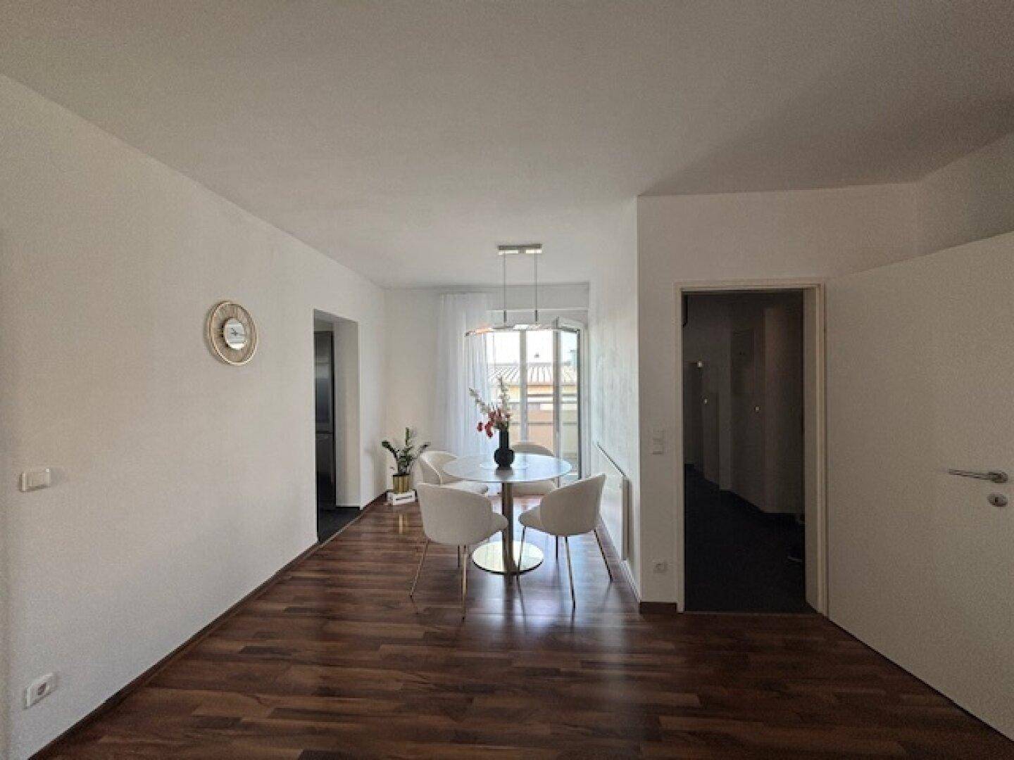Heller Essbereich mit rundem Tisch, modernen Stühlen und Zugang zu einem Balkon.