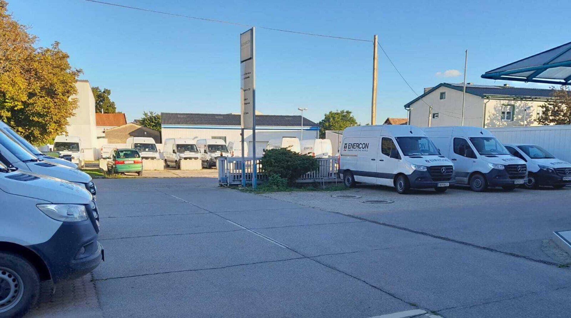 Außenbereich mit mehreren Lieferwagen auf einem gepflasterten Parkplatz unter blauem Himmel.