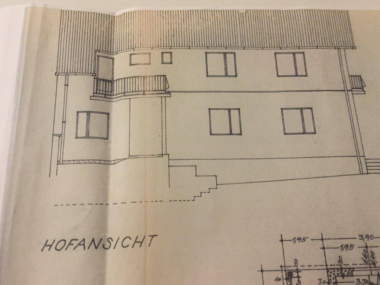 Hofansicht des Gebäudes mit Fenstern, Türen und einem Balkon.