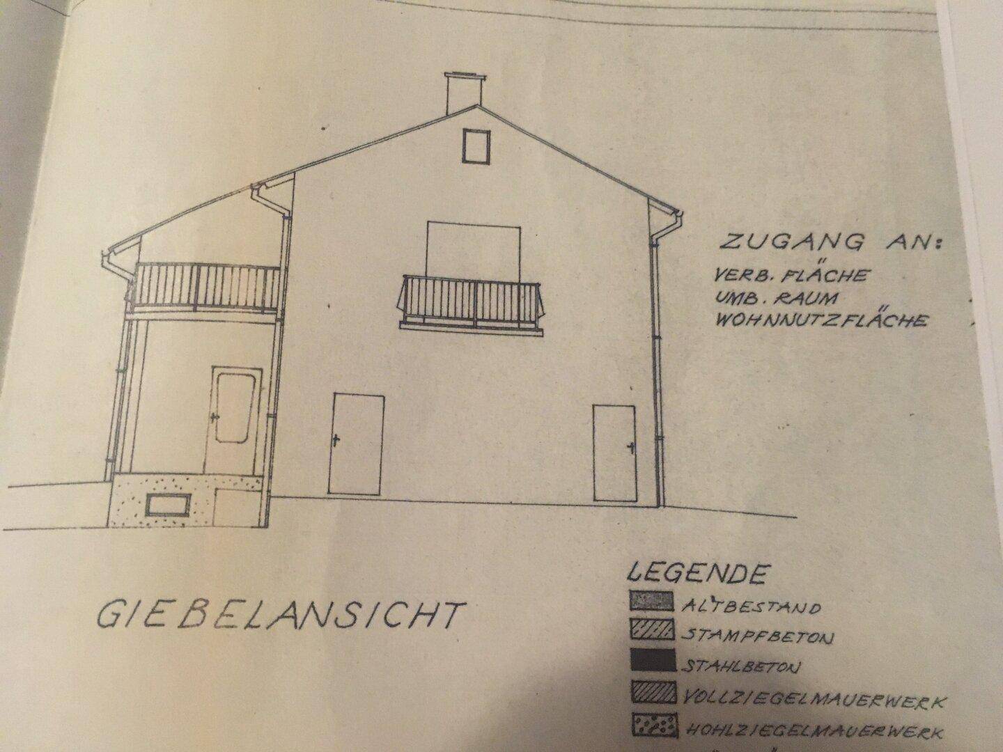 Giebelansicht des Hauses mit Balkonen und Legende zu den Baumaterialien.