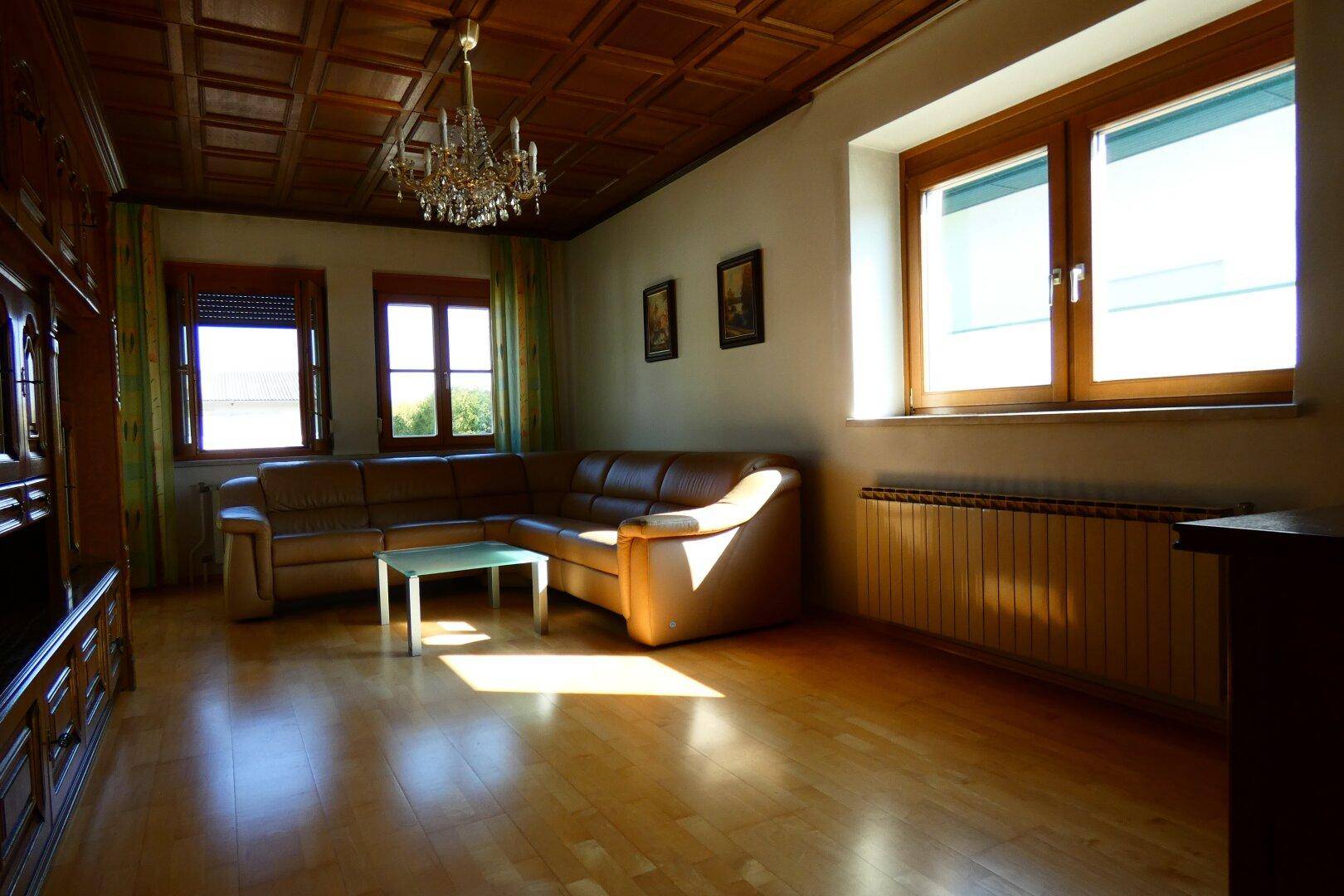 Helles Wohnzimmer mit Holzkassettendecke, Parkettboden und bequemer Ledercouch.