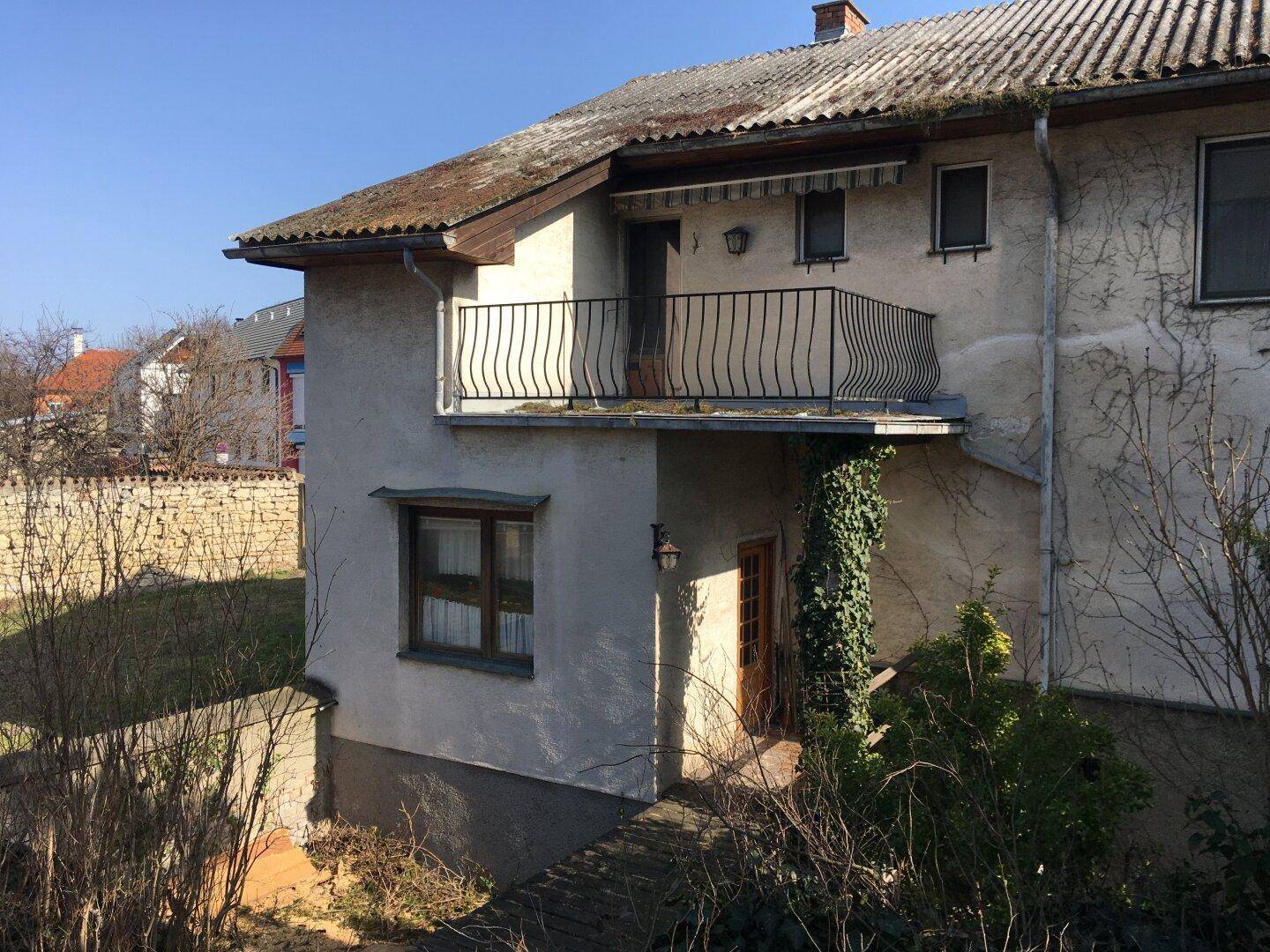 Seitenansicht des Hauses mit einem kleinen Balkon und verputzter Fassade.