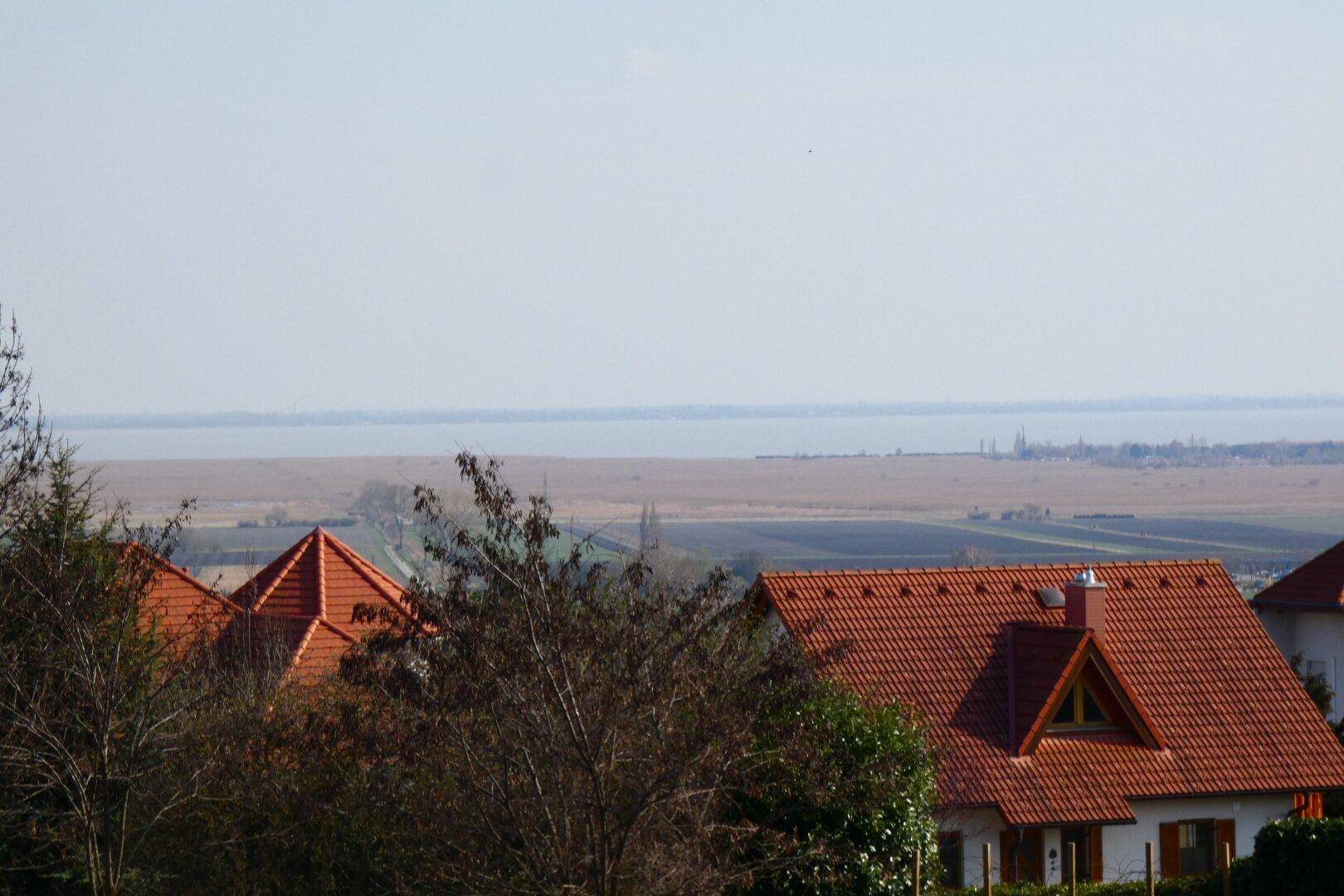 Panoramablick über rote Dächer auf einen weit entfernten See und die umliegende Landschaft.