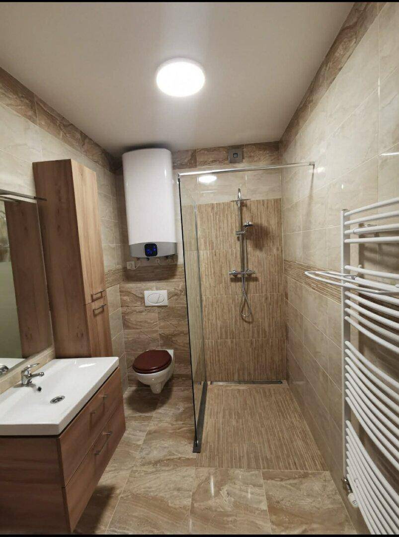 Modernes Badezimmer mit begehbarer Dusche, Waschtisch und beheiztem Handtuchhalter.