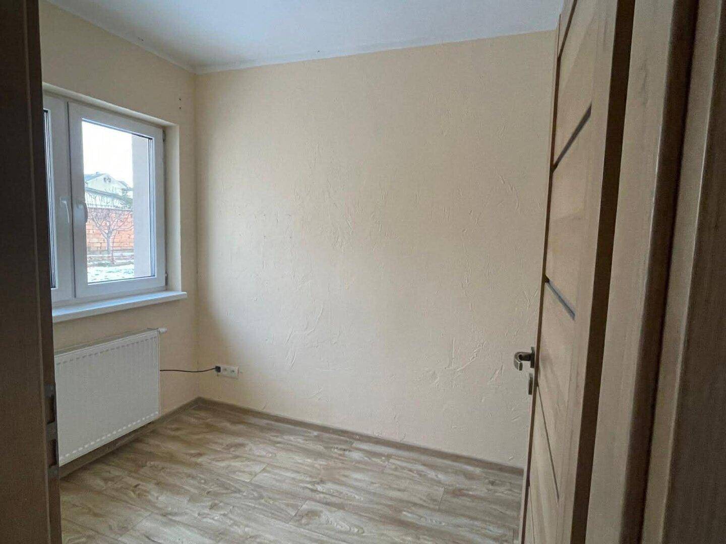 Kleines, helles Zimmer mit Fenster und Laminatboden, ideal als Kinder- oder Arbeitszimmer.