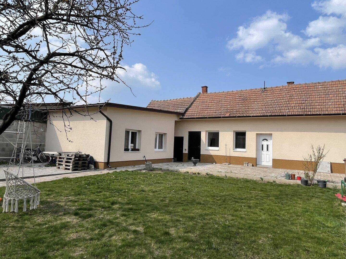 Weitläufiger Garten mit Rasenfläche und Blick auf die Rückseite des Hauses.