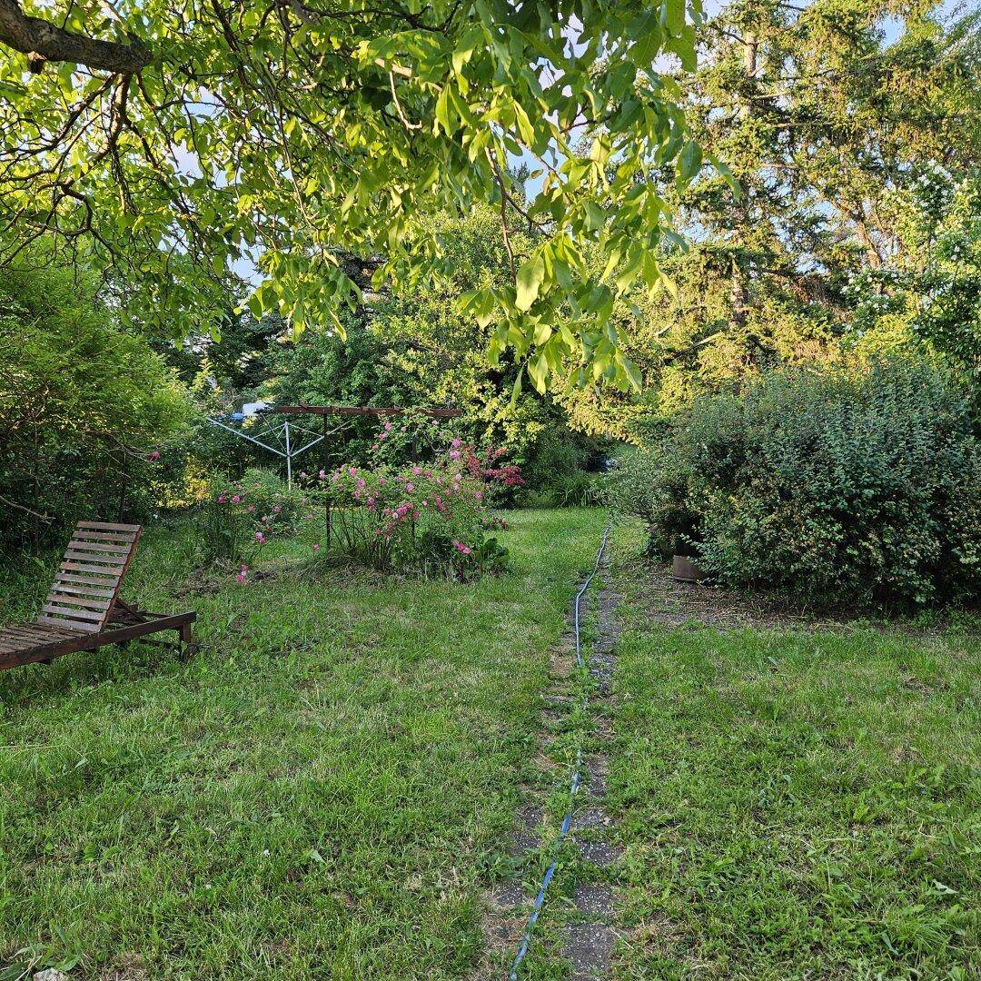 Großer, gepflegter Garten mit Rasenfläche, Bäumen und einem Liegestuhl.