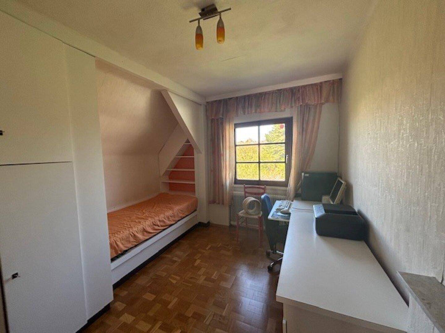 Gemütliches Schlafzimmer im Dachgeschoss mit Schräge, Einzelbett und Schreibtisch.