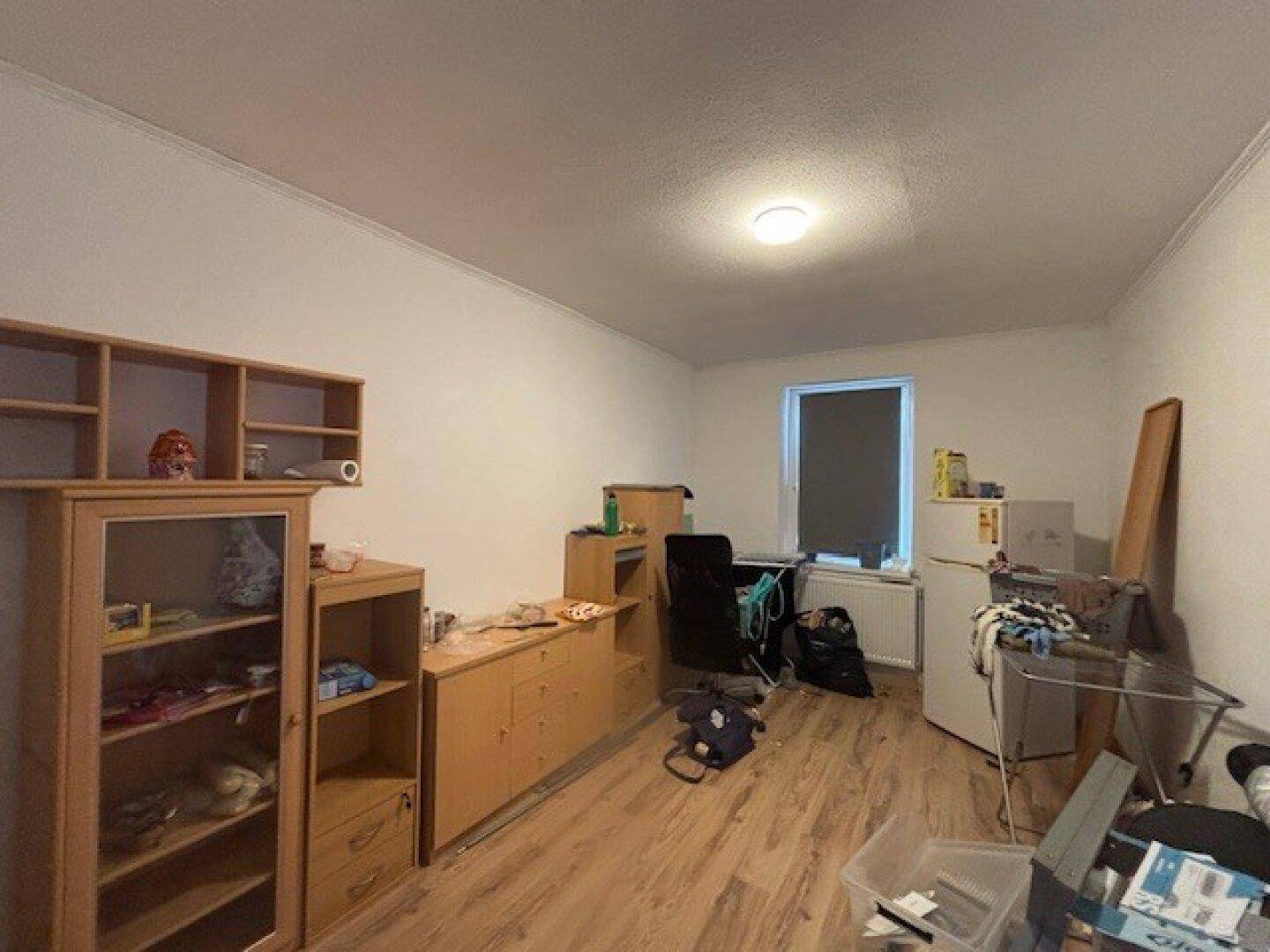 Geräumiges Zimmer mit Laminatboden, Schränken und einem Fenster, ideal als Schlaf- oder Arbeitszimmer.
