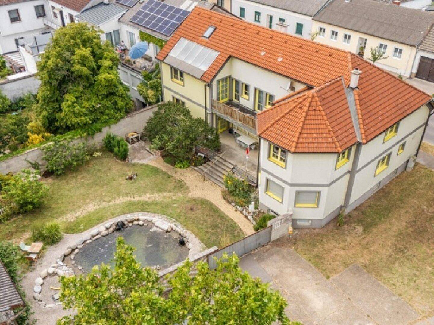 Luftaufnahme des Anwesens mit großem Garten, Teich und Wohnhaus.