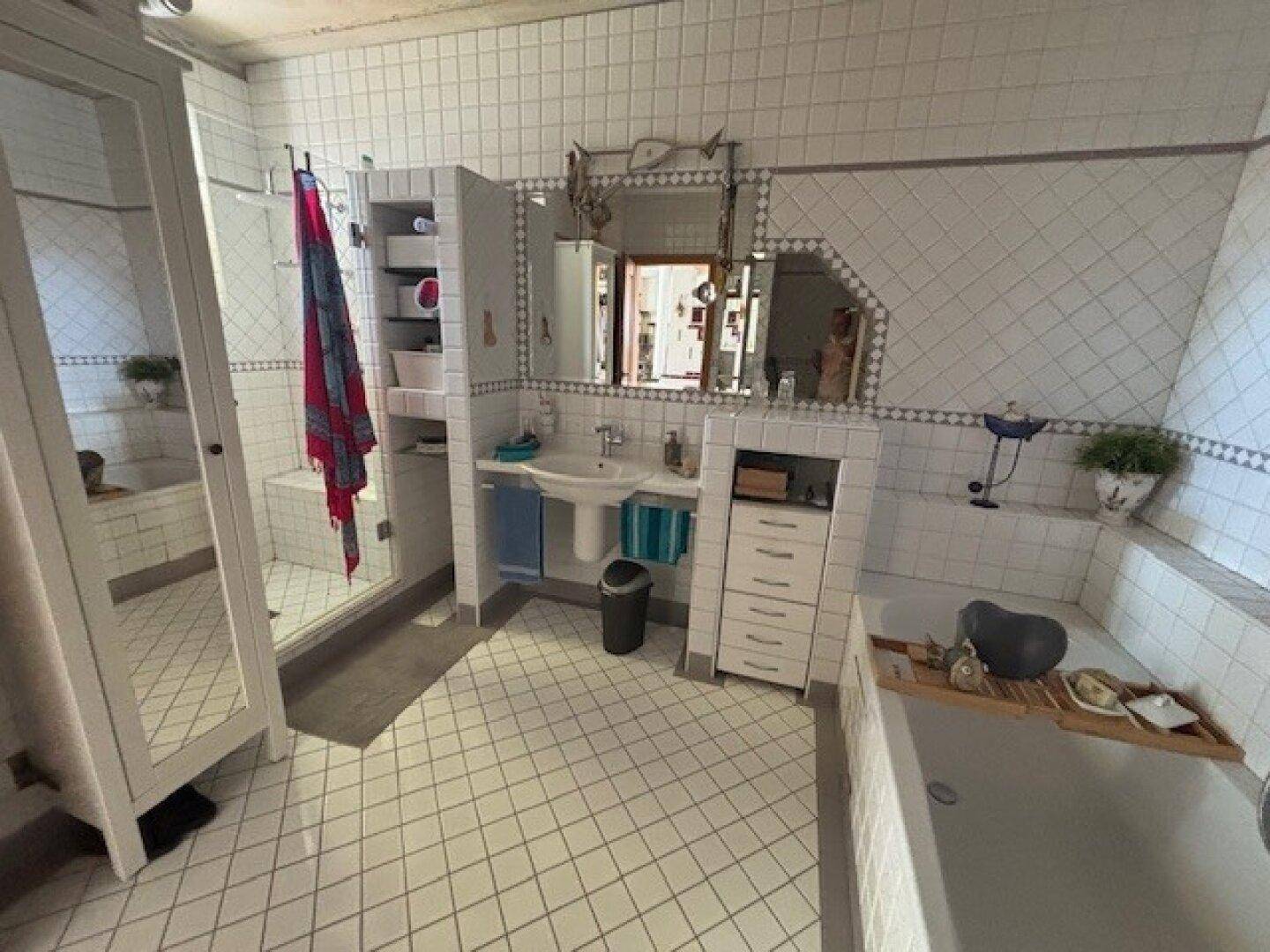 Helles Badezimmer mit weißen Fliesen, Badewanne und separater Duschkabine.