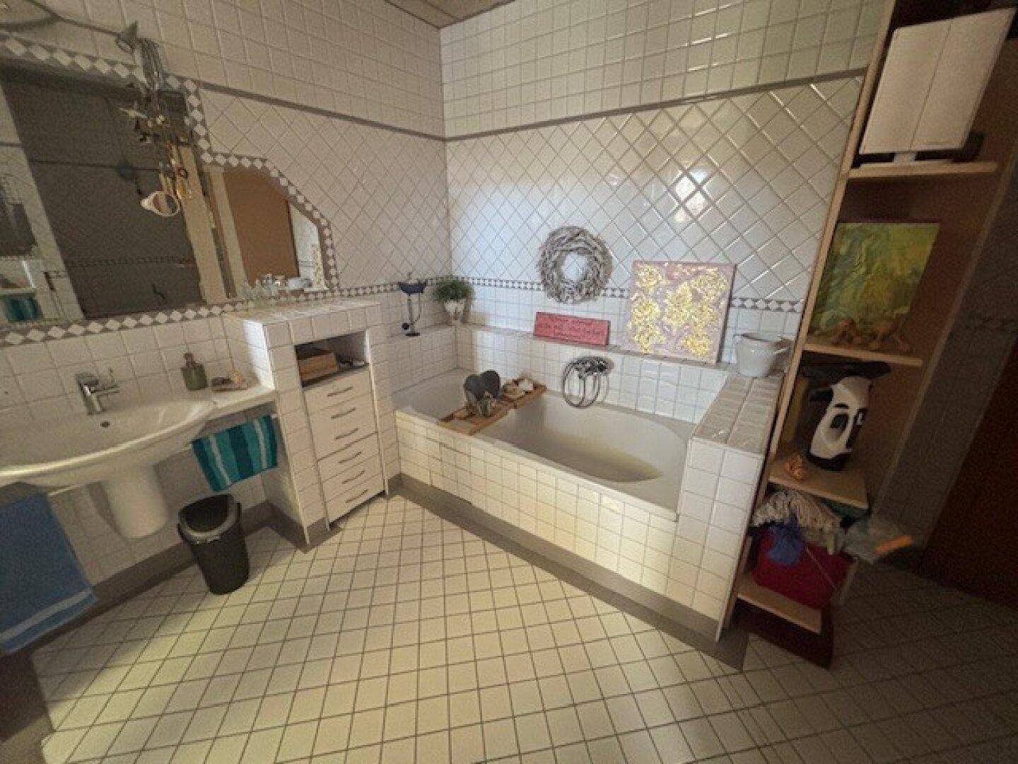 Badezimmer mit Badewanne, Waschbecken und weißen Fliesen im klassischen Stil.
