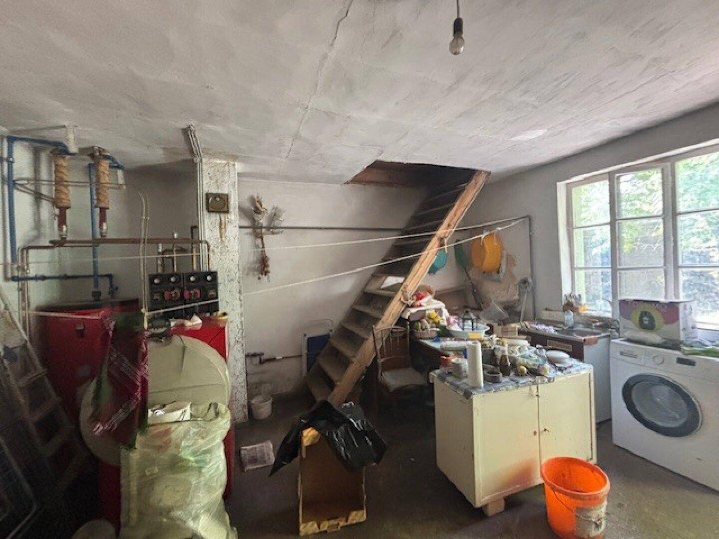 Hauswirtschaftsraum im Keller mit Heizungsanlagen, Waschmaschine und Fenster.