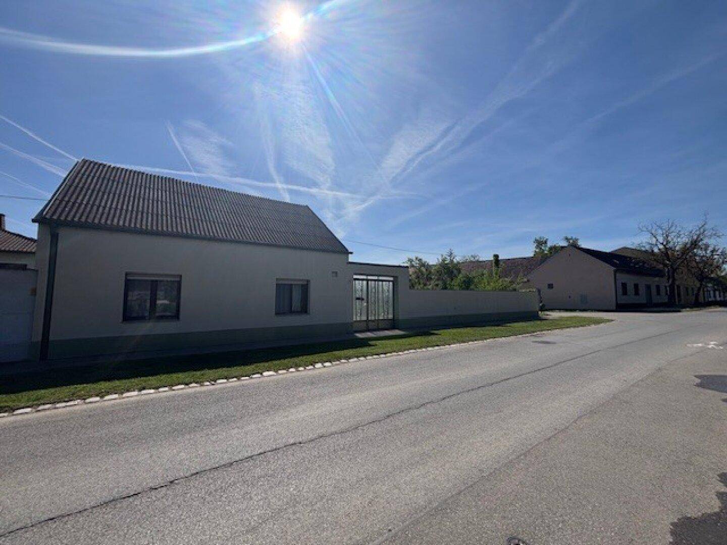 Blick auf die ruhige Straße mit einem Gebäude und einem Tor im Hintergrund unter blauem Himmel.