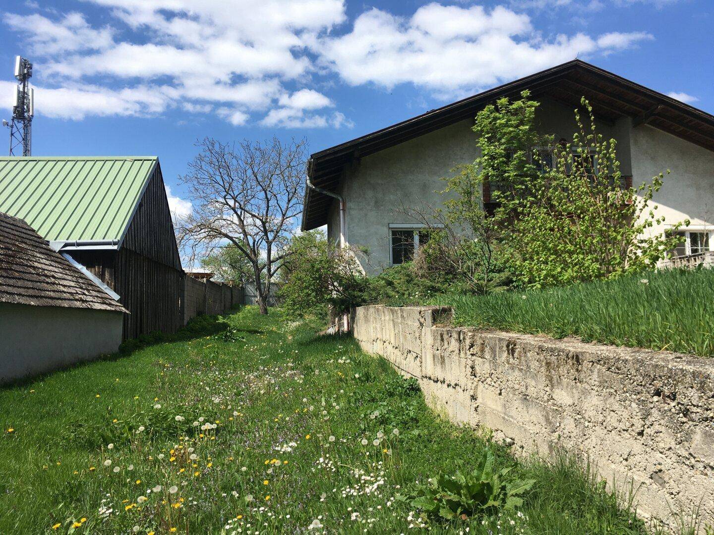 Zwei Häuser mit unterschiedlichen Dachformen und Fassaden, umgeben von einer grünen Wiese.